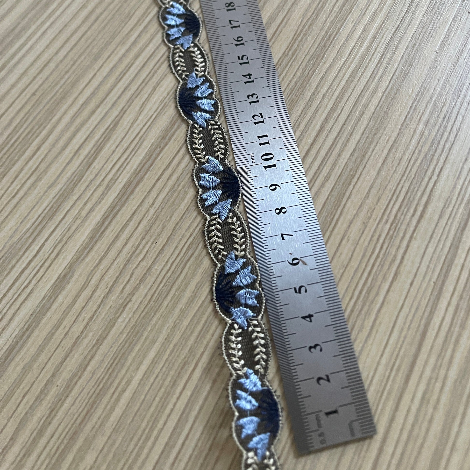 Attēls ar Izšūta mežģīnes lenta 2 cm - tumši zila ar bēšiem akcentiem – pieejams Šarlotes audumi