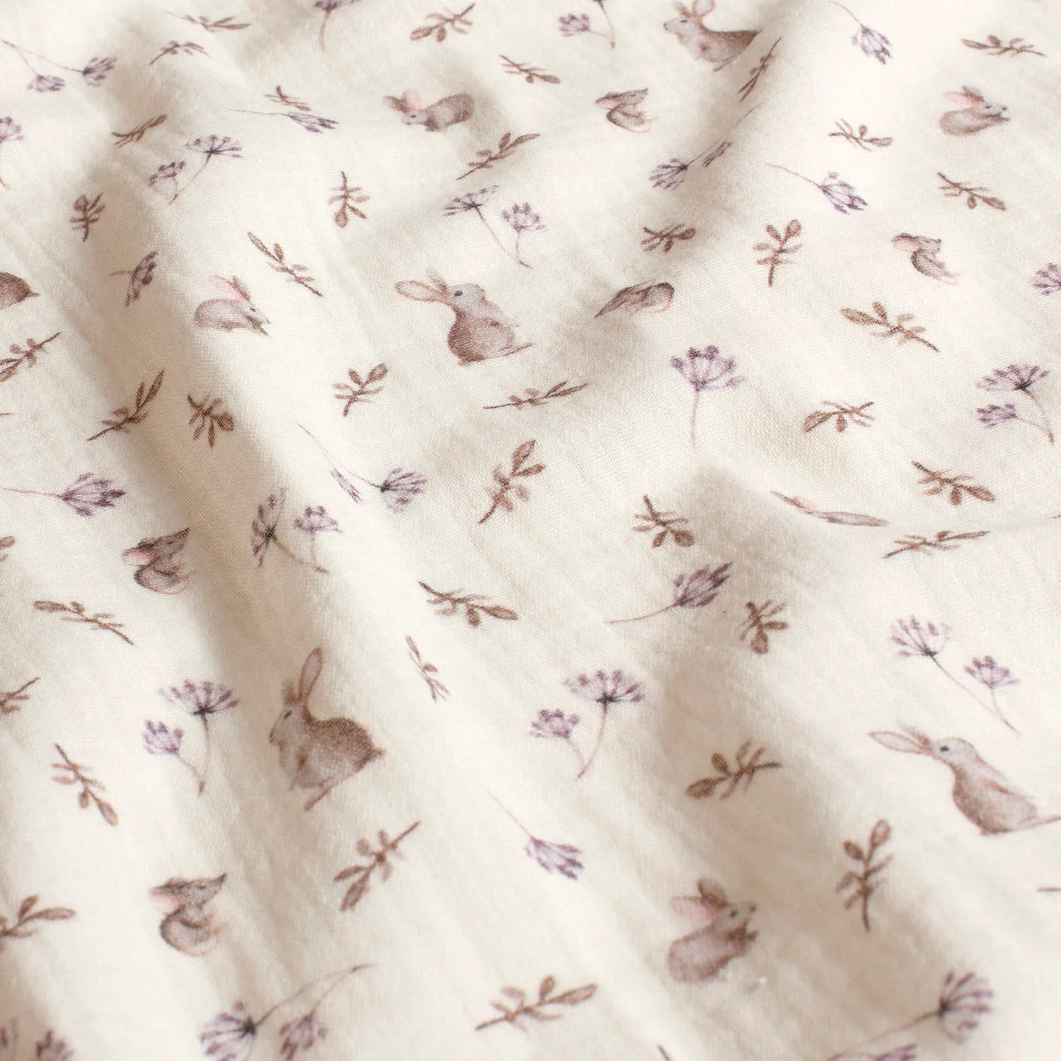 Attēls ar Muslīns - zaķi un ziedi uz piena balta 130 g/m² – pieejams Šarlotes audumi